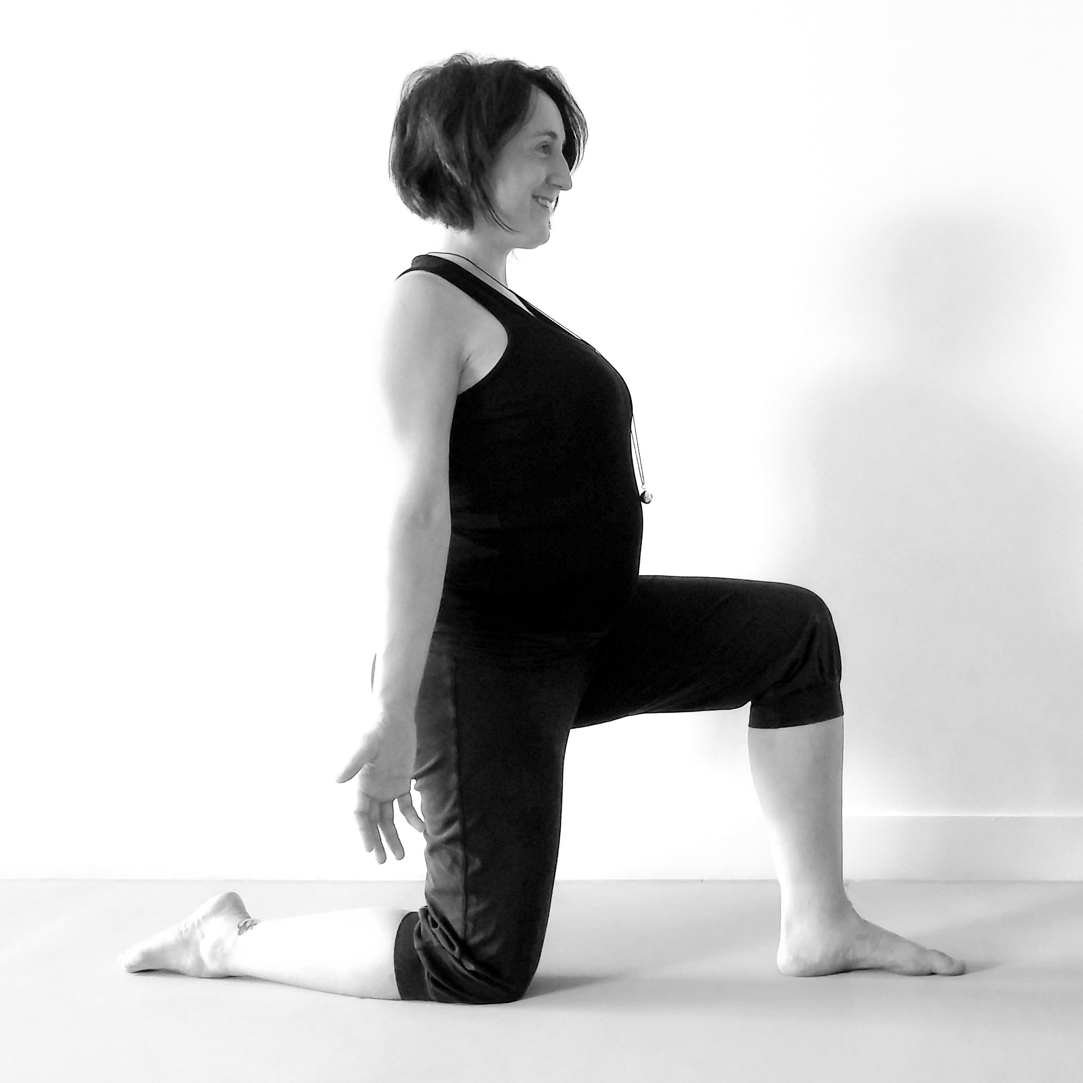 Future maman en posture un genou au sol et en fente avant lors d'un cours de Yoga prénatal