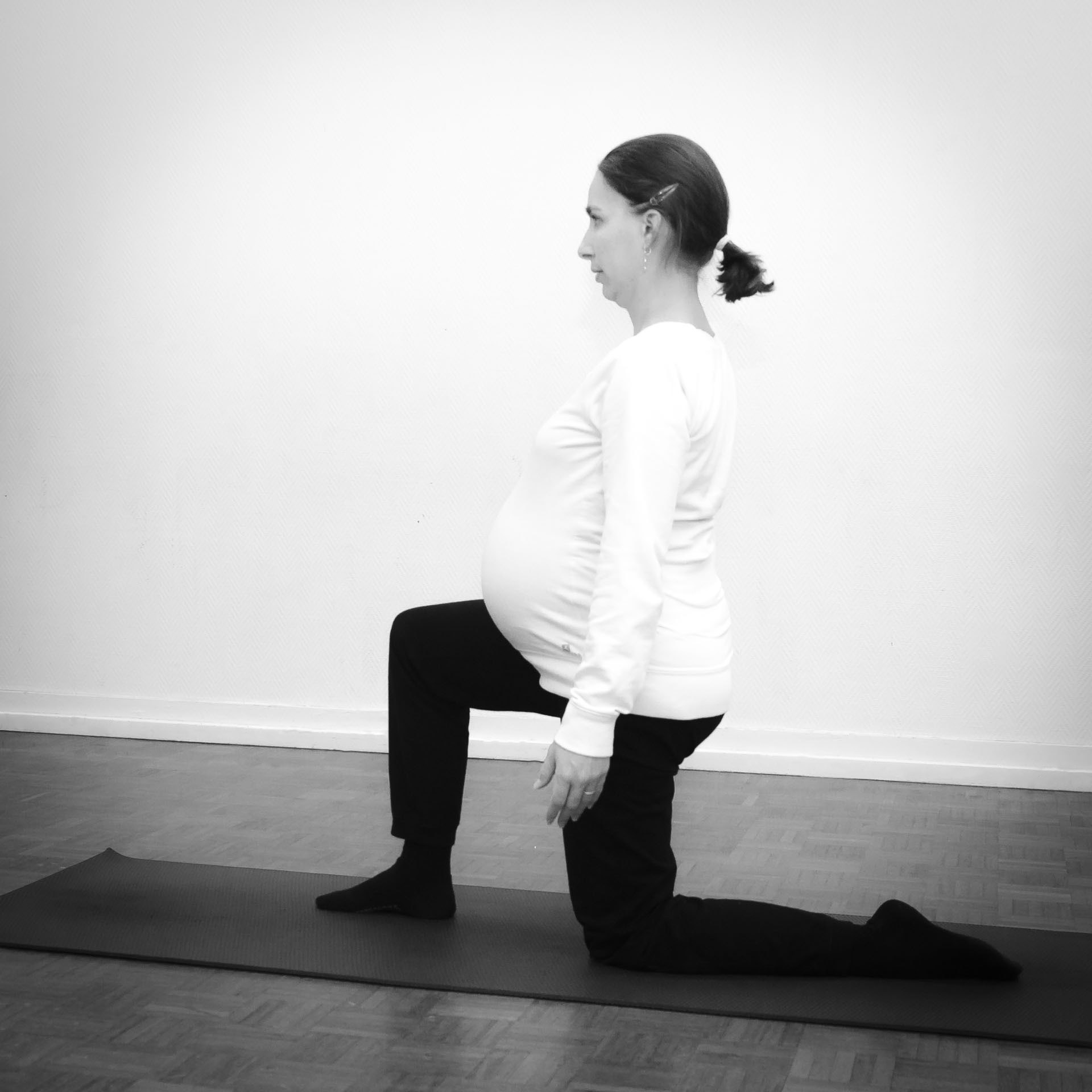 Future maman en posture sur un genou lors d'un cours de Yoga prénatal