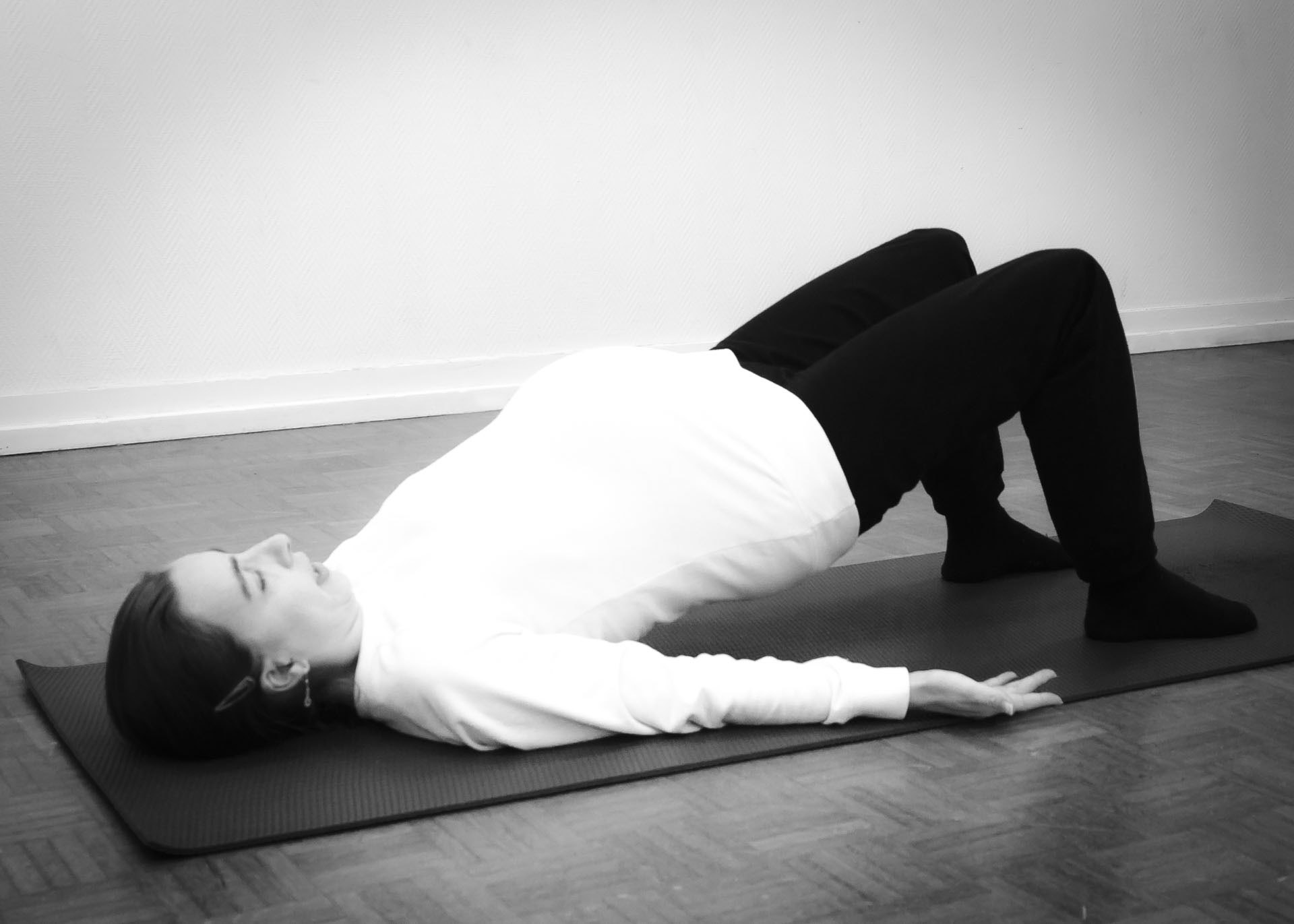 Future maman en posture de demi-pont lors d'un cours de Yoga prénatal