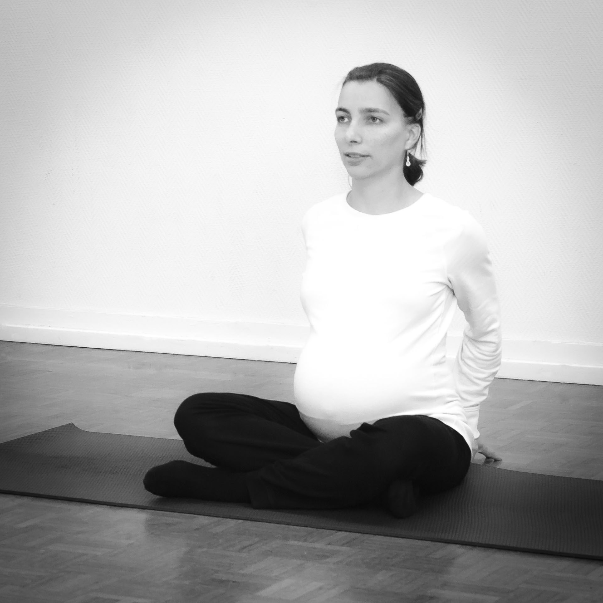 Future maman en posture d'étirement du dos lors d'un cours de Yoga prénatal